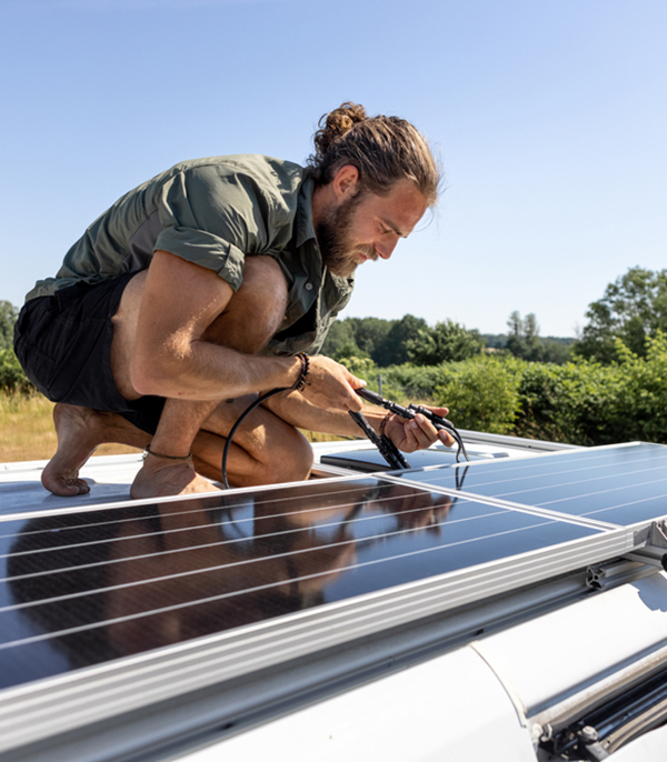 Man installing solar panels on top of a caravan